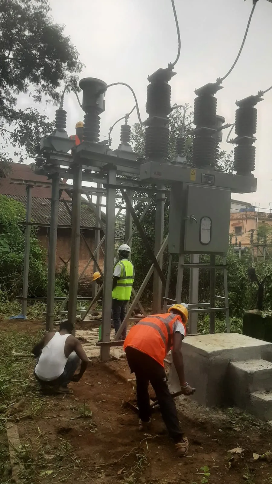 Worker kneeling at the base of a steel structure finishing the concrete pedestal