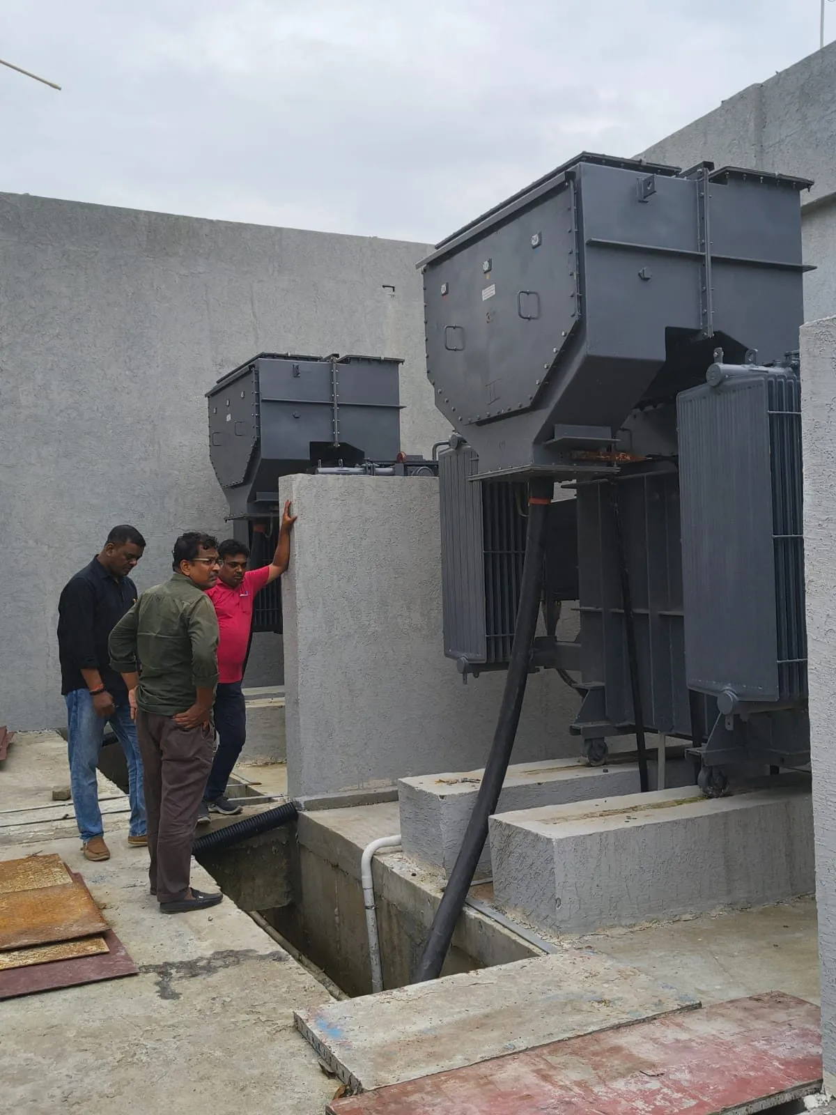 Three Ranisons crew members at the wall of a transformer bay during installation