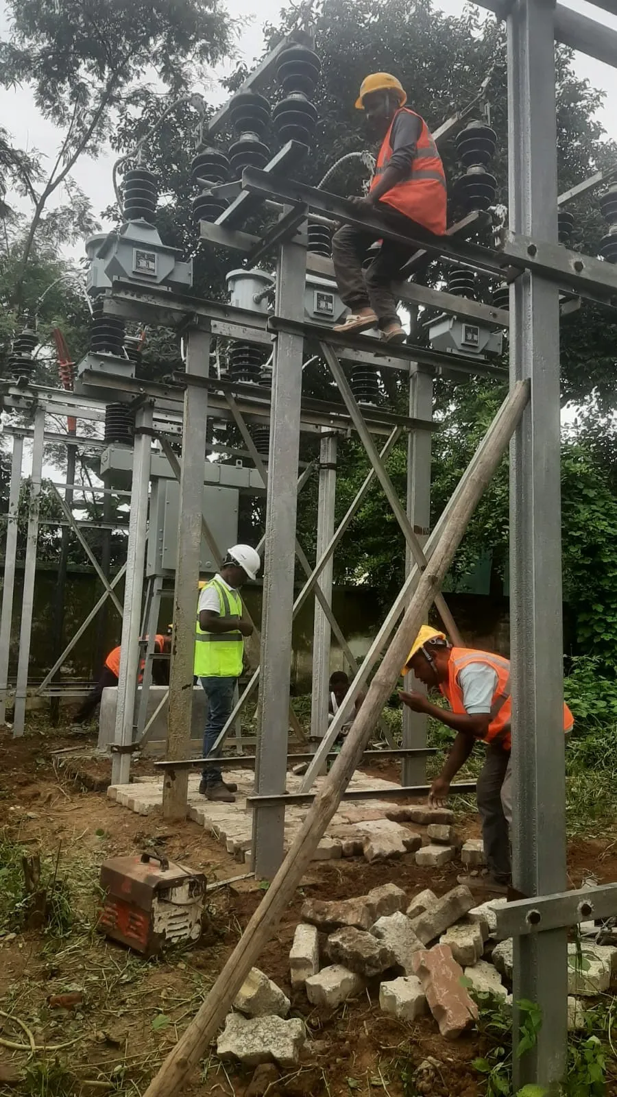 Worker seated on a cross-arm connecting high-tension switchgear